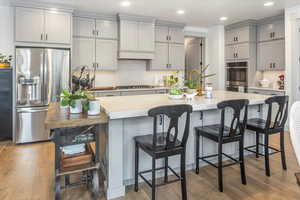 Kitchen featuring appliances with stainless steel finishes, a center island with sink, light hardwood / wood-style floors, and gray cabinetry