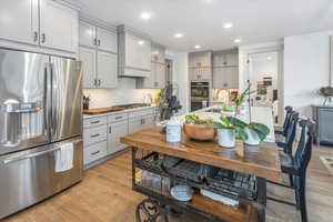 Kitchen with gray cabinetry, light hardwood / wood-style flooring, stainless steel appliances, and sink