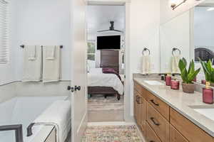 Bathroom featuring vanity, ceiling fan, and a washtub