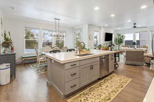 Kitchen featuring gray cabinetry, a kitchen island with sink, sink, stainless steel dishwasher, and a healthy amount of sunlight