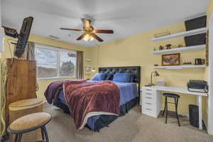 Carpeted bedroom featuring ceiling fan