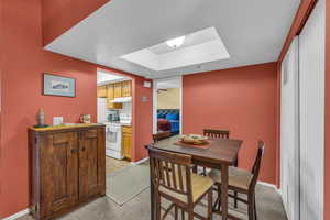 Dining room with a skylight and light carpet