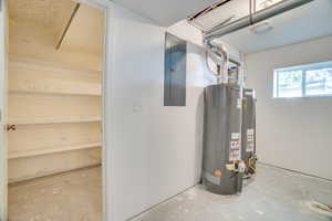 Utilities with (2) gas water heaters and electric panel, view into storage room