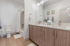 Full bathroom featuring hardwood / wood-style floors, vanity, toilet, and shower / tub combo with curtain