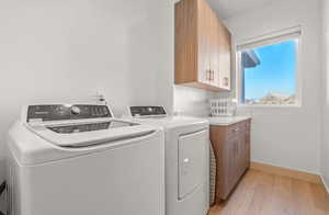 Laundry area featuring light hardwood / wood-style floors, cabinets, and washing machine and clothes dryer