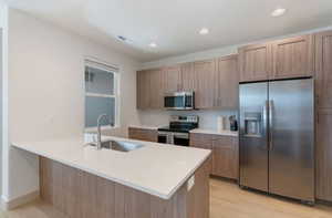 Kitchen featuring sink, light brown cabinets, stainless steel appliances, light hardwood / wood-style flooring, and kitchen peninsula