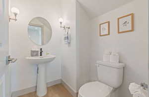 Bathroom featuring hardwood / wood-style flooring, toilet, and lofted ceiling