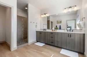 Bathroom with a tile shower, vanity, and hardwood / wood-style flooring