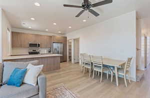 Kitchen with kitchen peninsula, stainless steel appliances, ceiling fan, and light hardwood / wood-style floors