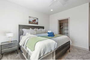 Carpeted bedroom featuring a walk in closet, ceiling fan, and a closet