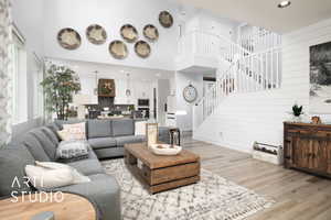 Living room featuring wooden walls, a towering ceiling, and light hardwood / wood-style floors