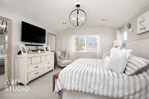 Carpeted bedroom featuring a chandelier, lofted ceiling, and multiple windows