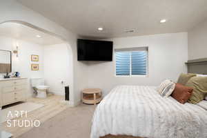 Bedroom with a textured ceiling, light hardwood / wood-style floors, and sink