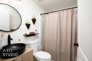 Bathroom with a textured ceiling, toilet, and sink