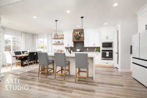 Kitchen with white cabinetry, an island with sink, pendant lighting, and appliances with stainless steel finishes