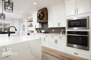 Kitchen featuring light stone countertops, white cabinets, pendant lighting, and appliances with stainless steel finishes