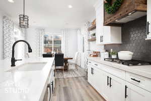 Kitchen featuring sink, white cabinets, pendant lighting, and light wood-type flooring