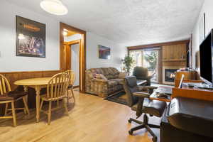 Office area with a textured ceiling, light hardwood / wood-style floors, and wood walls