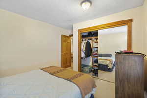 Bedroom with carpet, a textured ceiling, and a closet