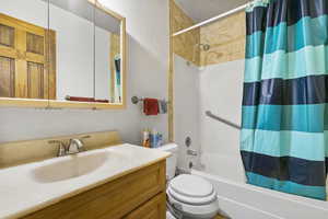 Full bathroom featuring shower / bath combo with shower curtain, vanity, and toilet