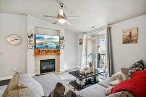 Living room featuring ceiling fan, a fireplace, lofted ceiling, and light wood-type flooring