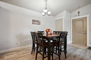 Dining area with wood-type flooring, lofted ceiling, and an inviting chandelier