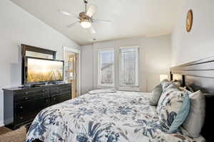 Bedroom featuring ceiling fan, dark carpet, and lofted ceiling