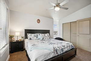 Carpeted bedroom with ceiling fan, a closet, and lofted ceiling