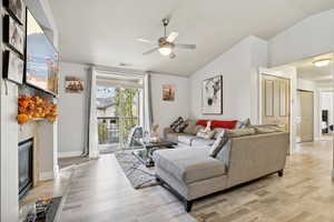 Living room with light hardwood / wood-style floors, vaulted ceiling, and ceiling fan