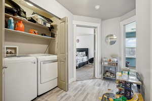 Washroom with washer and clothes dryer and light wood-type flooring