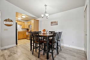 Dining area featuring a chandelier, light hardwood / wood-style flooring, and lofted ceiling