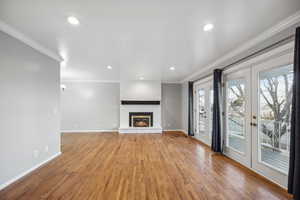 Unfurnished living room with a fireplace, french doors, light hardwood / wood-style flooring, and crown molding