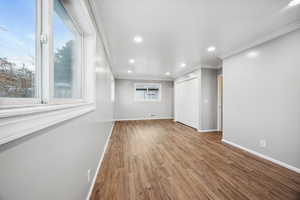 Primary bedroom with ornamental molding, light wood-type flooring, and a healthy amount of sunlight