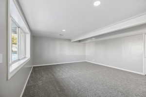 Unfurnished room featuring beam ceiling and carpet floors