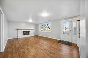 Foyer entrance featuring wood-type flooring and a brick fireplace