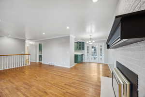 Unfurnished living room featuring crown molding, a chandelier, and light wood-type flooring