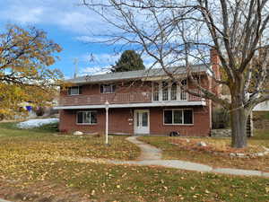 Front of property with a wooden deck and a front yard