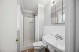 Primary bathroom with sink, tile patterned flooring, toilet, a shower with shower door, and ornamental molding