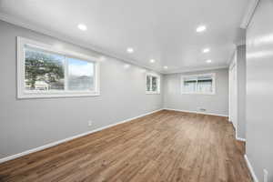 Primary bedroom with hardwood / wood-style flooring and crown molding