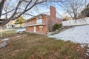 Snow covered house featuring a yard and a balcony