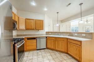 Kitchen with sink, stainless steel appliances, hanging light fixtures, and a chandelier