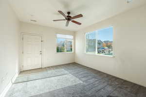 Empty room with ceiling fan and light carpet