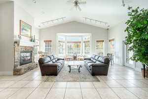 Tiled living room featuring a textured ceiling, ceiling fan, a fireplace, and track lighting