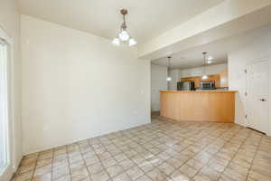 Kitchen with a notable chandelier, light brown cabinets, kitchen peninsula, and appliances with stainless steel finishes