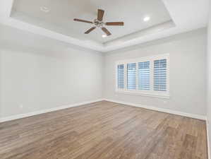 Unfurnished room featuring hardwood / wood-style flooring, a raised ceiling, and ceiling fan