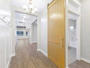 Hallway featuring a barn door, an inviting chandelier, and hardwood / wood-style flooring