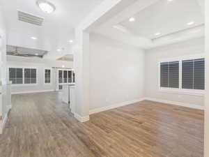 Unfurnished room with hardwood / wood-style flooring, ceiling fan, and a tray ceiling