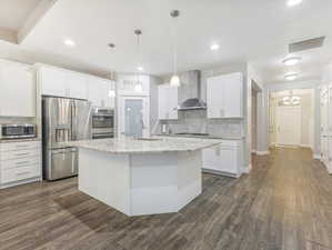 Kitchen with white cabinets, sink, wall chimney exhaust hood, dark hardwood / wood-style floors, and appliances with stainless steel finishes