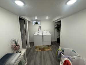 Laundry room featuring washing machine and clothes dryer, a textured ceiling, and dark hardwood / wood-style floors