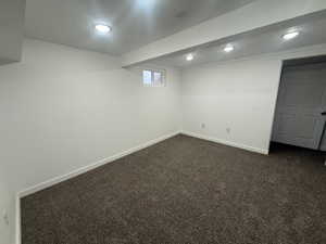 Basement featuring dark colored carpet and a textured ceiling